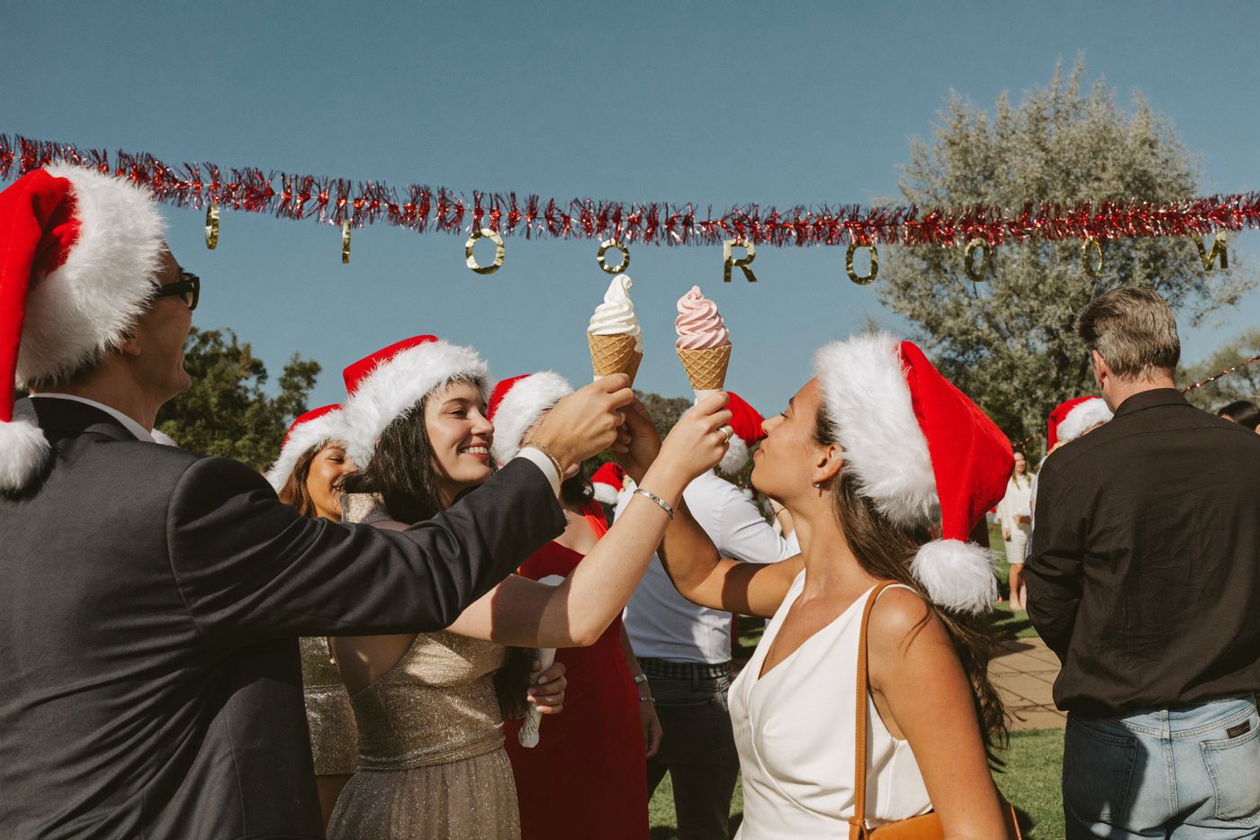 Colleagues in santa hats toasting with soft-serve cones at a summer Christmas party