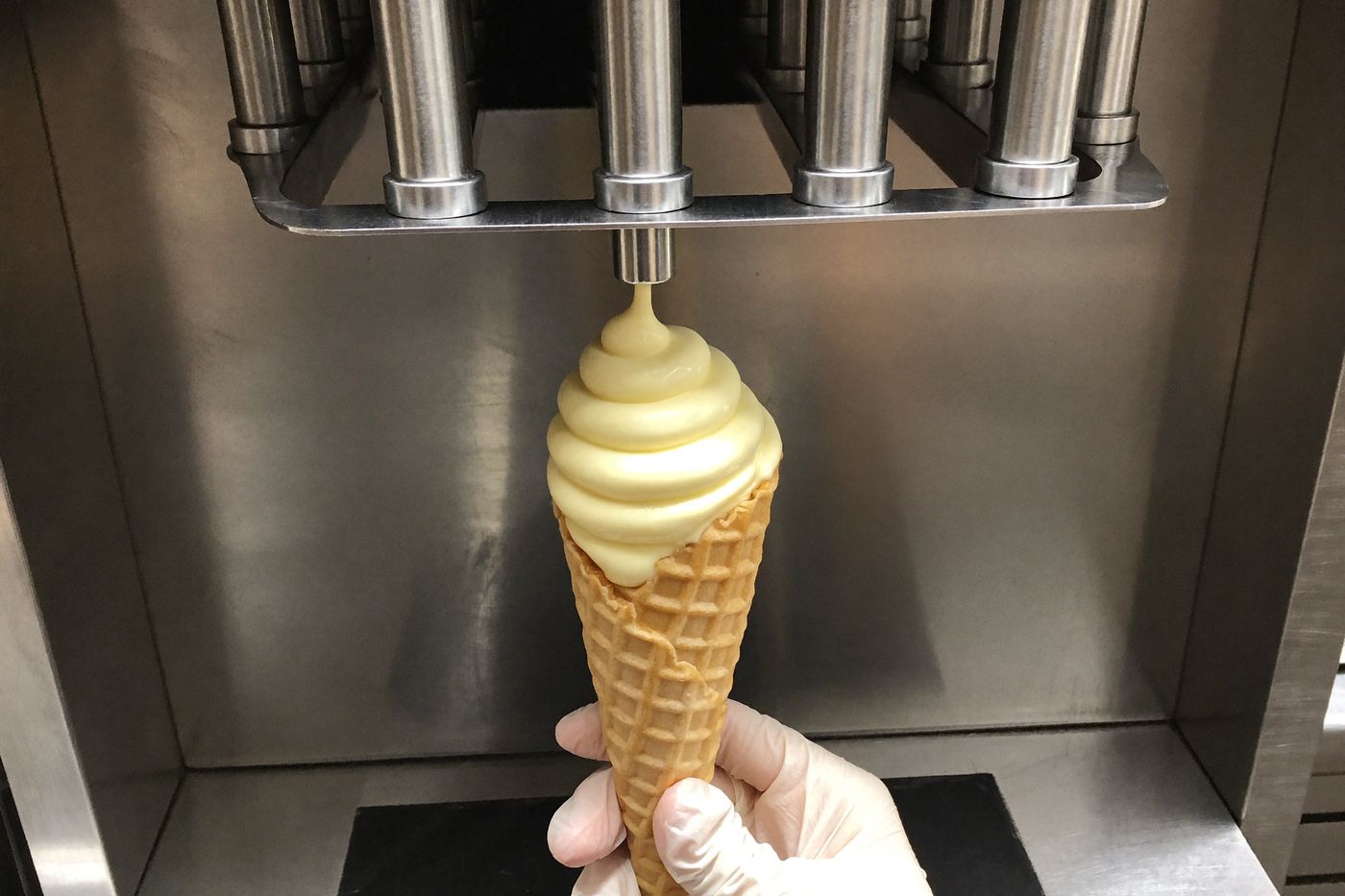 Soft-serve machine dispensing a vanilla swirl into a waffle cone