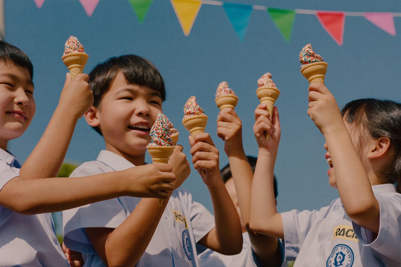 School kids holding soft-serve cones with sprinkles at a fete